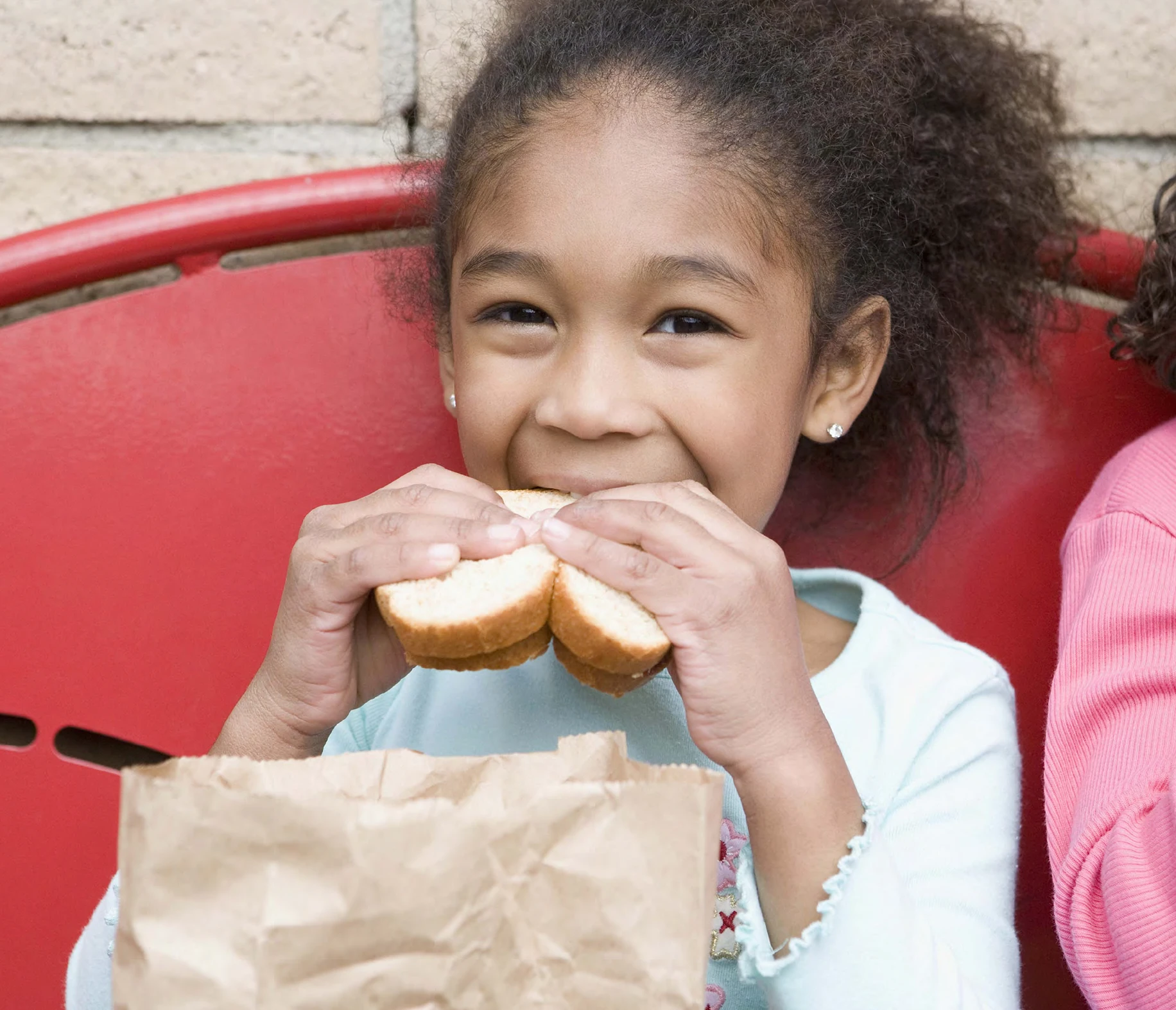 Child eating a sandwich outdoors
