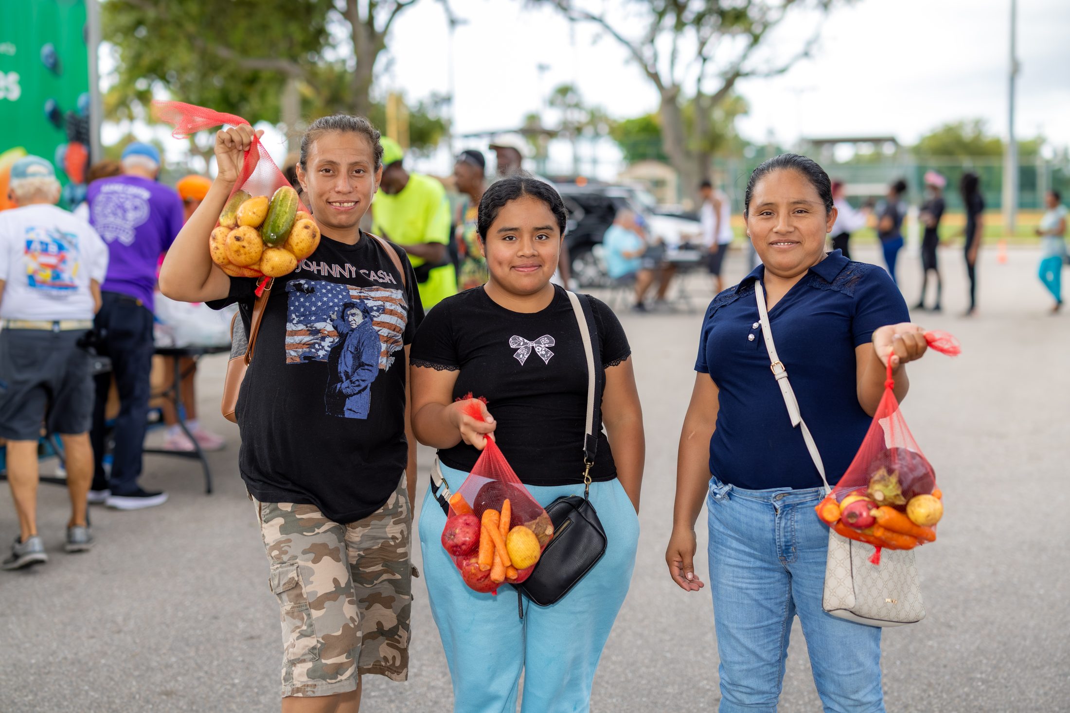 Neighbors carrying bags of fresh produce at a Harry Chapin Food Bank distribution