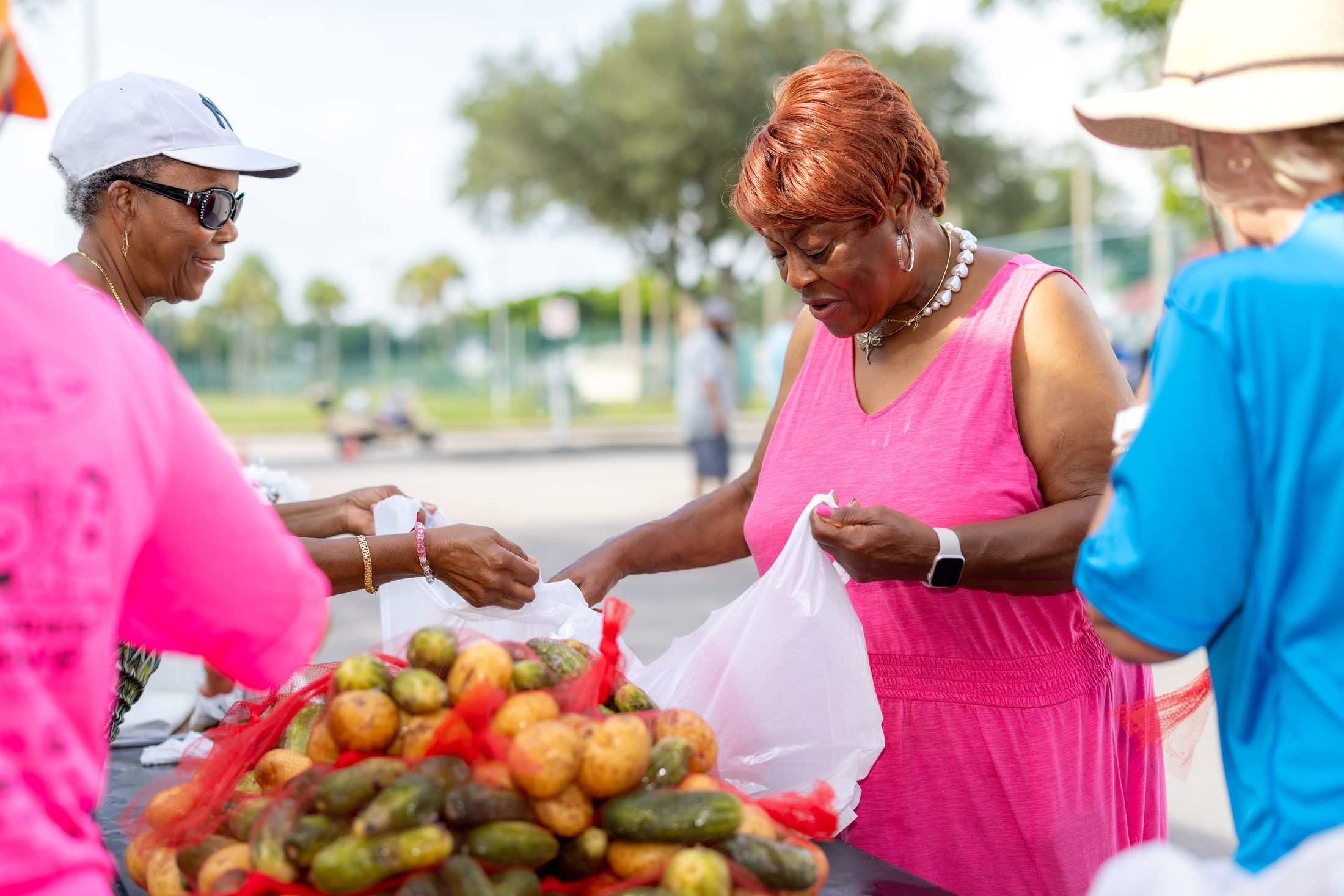 A volunteer handing a bag of fresh produce to a neighbor at a food distribution
