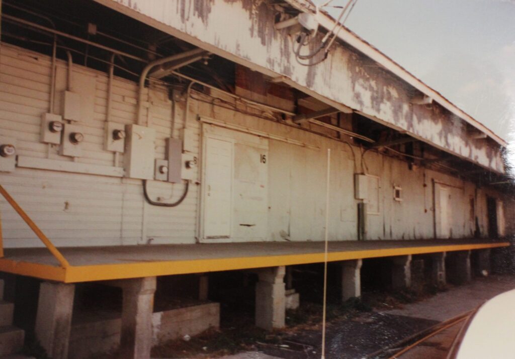 A weathered warehouse loading dock with a long row of doors.
