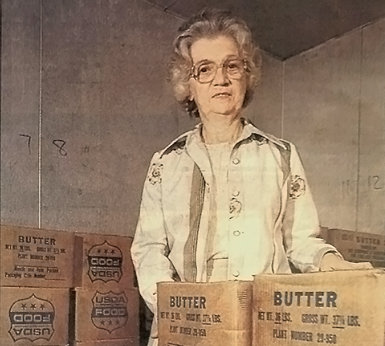 Dee Baker, the food bankโs first full-time director, with cases of USDA butter.